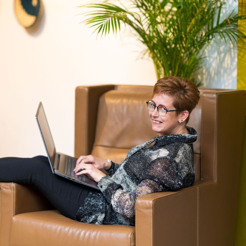Gerrie met laptop op schoot in een grote fauteuil
